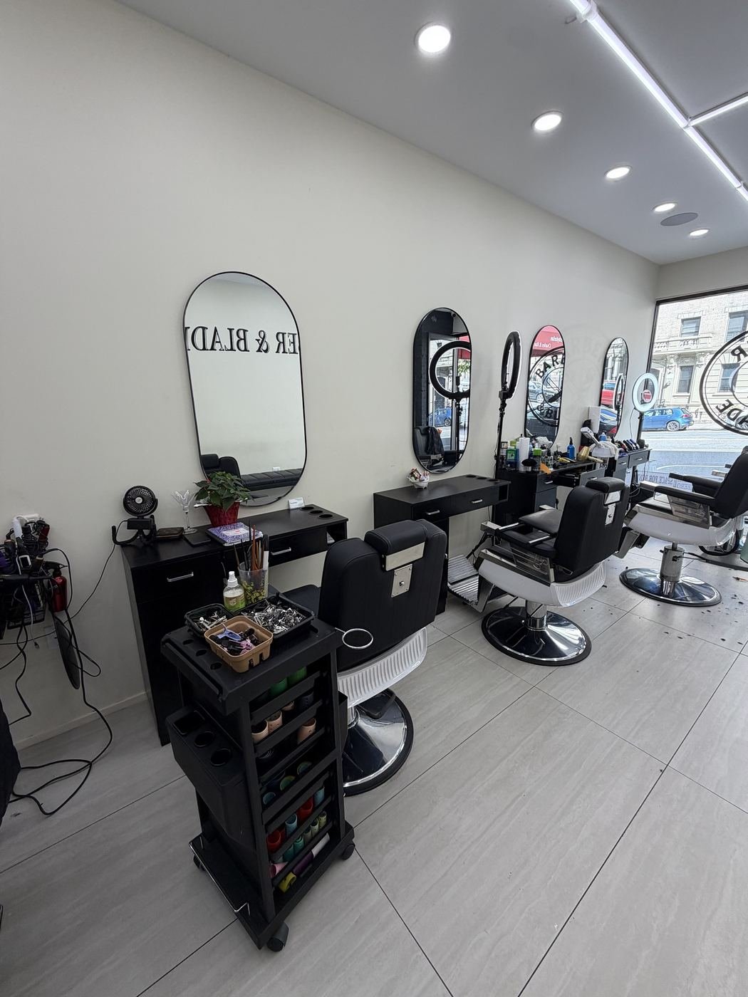 Barber chairs and oval mirrors at Barber & Blade barbershop on W 135th St